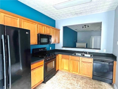 Kitchen featuring black appliances, dark laminate countertops, and a textured ceiling