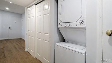 Laundry room with light wood-type flooring and stacked washer / drying machine