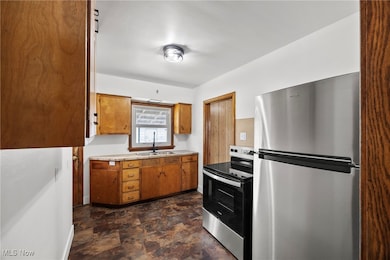 Kitchen featuring stainless steel appliances, brown cabinets, stone finish floors, and tile counters