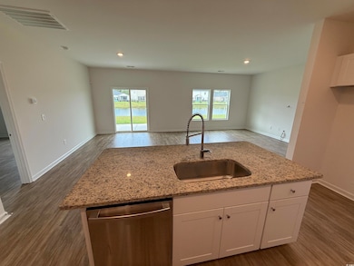 Kitchen with dark wood-style flooring, dishwasher, white cabinetry, light stone counters, and recessed lighting