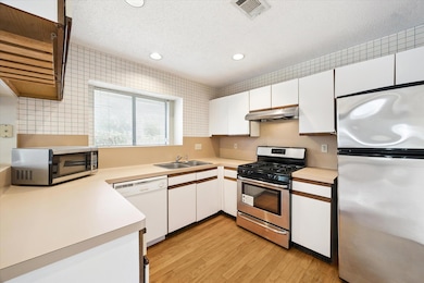 Kitchen with stainless steel appliances, white cabinetry, recessed lighting, a textured ceiling, and light countertops