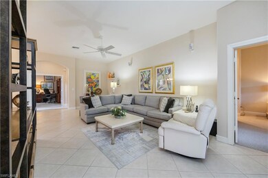 Living room featuring arched walkways, light tile patterned flooring, a desk, and a ceiling fan