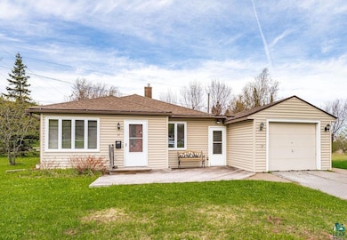 Front view of property featuring a chimney, a yard, a garage, driveway, and a shingled roof
