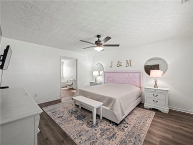 Bedroom with a textured ceiling, baseboards, and d