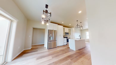 Kitchen featuring glass insert cabinets, stainless steel appliances, recessed lighting, white cabinets, and decorative light fixtures
