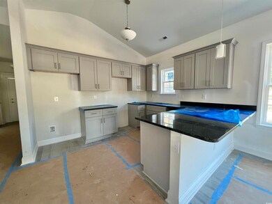 Kitchen featuring gray cabinetry, pendant lighting