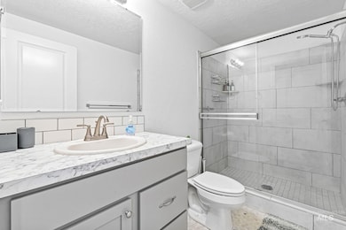 Bathroom featuring vanity, a stall shower, a textured ceiling, and backsplash