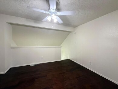 Empty room featuring ceiling fan, a textured ceil