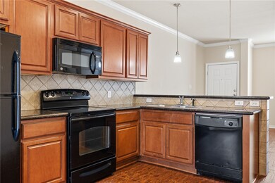Kitchen with black appliances, crown molding, dark