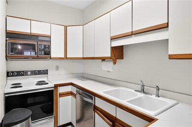 Kitchen with white range with electric cooktop, stainless steel dishwasher, white cabinets, and light countertops