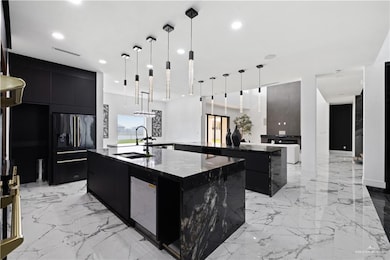 Kitchen with a large island with sink, high quality fridge, modern cabinets, dark cabinetry, and recessed lighting