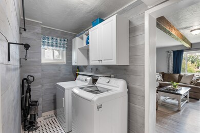 Laundry room featuring wood walls, washing machine and dryer, cabinet space, and a textured ceiling