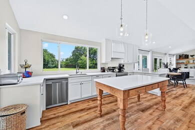 Kitchen with stainless steel appliances, lofted ceiling, light countertops, white cabinets, and light wood-style floors