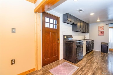 Kitchen with black gas range, dark wood-type flooring, recessed lighting, and white dishwasher