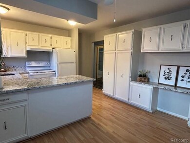 Kitchen featuring white cabinetry, light wood-style floors, light stone counters, and a peninsula
