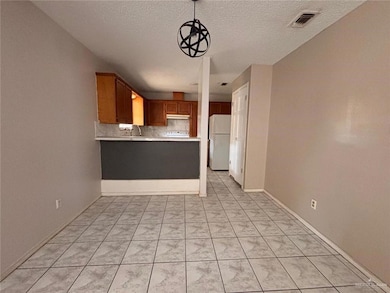 Kitchen with backsplash, a textured ceiling, decorative light fixtures, kitchen peninsula, and white fridge
