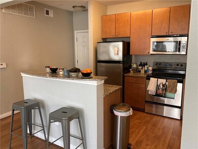 Kitchen featuring stainless steel appliances, a kitchen breakfast bar, dark wood-type flooring, dark stone countertops, and a kitchen island