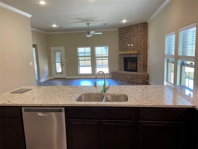 Kitchen featuring crown molding, stainless steel dishwasher, hardwood / wood-style floors, and a brick fireplace