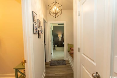 Hall featuring dark wood-type flooring and a chandelier