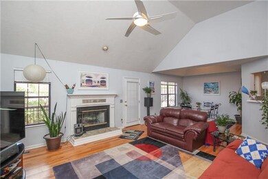 The living room has a vaulted ceiling, a ceiling fan and a fireplace. It is also open to the dining room