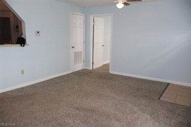 Unfurnished room with dark colored carpet and ceiling fan