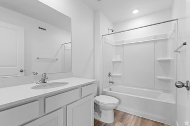 Full bathroom featuring wood finished floors, vanity, and washtub / shower combination