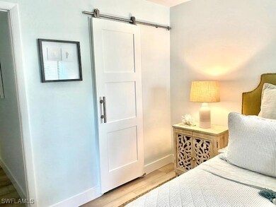 Bedroom with wood finished floors, baseboards, and a barn door