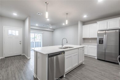 Kitchen featuring hanging light fixtures, stainless steel appliances, white cabinets, ceiling fan, and sink
