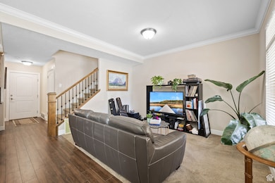 Living area featuring crown molding, stairway, and wood finished floors
