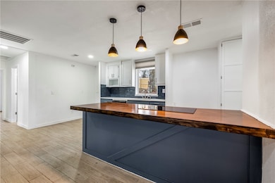 Wood and Quartz countertops provide a perfect balance of warmth and durability while the sleek electric cooktop enhances the spaces contemporary appeal