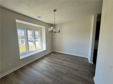 Unfurnished dining area featuring a chandelier, a textured ceiling, and dark wood finished floors