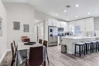 Kitchen featuring stainless steel appliances, vaulted ceiling, light wood-style flooring, a breakfast bar, and a peninsula