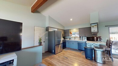 Kitchen featuring stainless steel appliances, light countertops, light wood-style floors, beam ceiling, and high vaulted ceiling