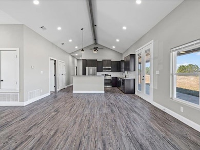 Kitchen featuring open floor plan, dark wood-type flooring, stainless steel appliances, a center island, and recessed lighting