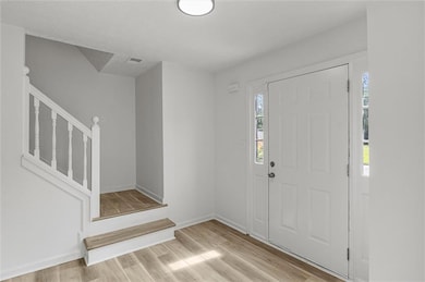 Foyer entrance with stairway, healthy amount of natural light, and wood finished floors