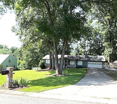View of front of property featuring a garage, a front yard, driveway, and a chimney