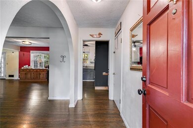 Corridor with dark wood-style flooring, a textured ceiling, baseboards, and arched walkways