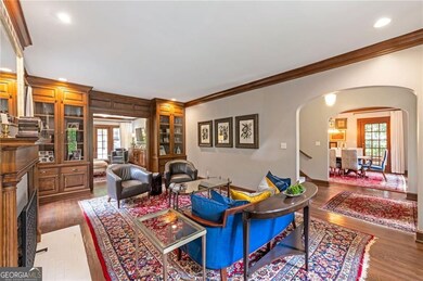 Living area featuring crown molding, arched walkways, a fireplace, recessed lighting, and wood finished floors