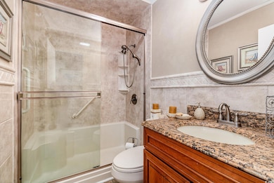 Bathroom with a shower stall, vanity, ornamental molding, toilet, and wainscoting