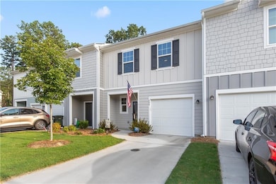 View of property with board and batten siding, a garage, driveway, and a front yard