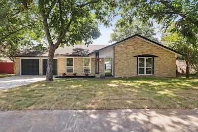 Mid-century inspired home featuring a garage, concrete driveway, brick siding, and a front lawn