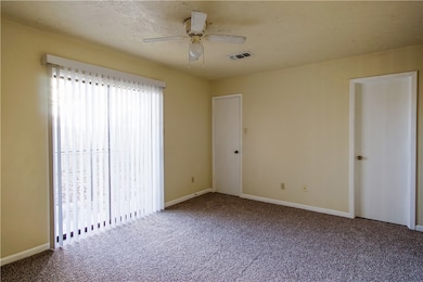 Carpeted empty room with a ceiling fan, baseboards