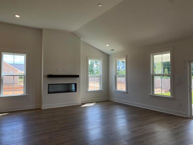 Unfurnished living room with a glass covered fireplace, dark wood-style floors, lofted ceiling, baseboards, and recessed lighting