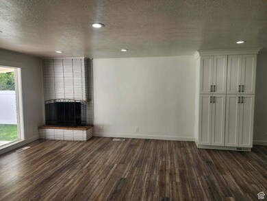 Unfurnished living room featuring a textured ceiling, a fireplace, dark wood-style floors, and recessed lighting