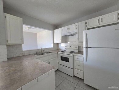 Kitchen featuring white cabinets, decorative backsplash, a sink, and white appliances