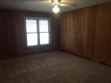 Unfurnished room with carpet, ceiling fan, and wood walls