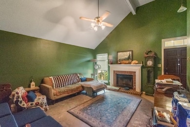Living area featuring high vaulted ceiling, beam ceiling, a brick fireplace, and ceiling fan