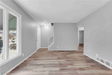 Spare room with stairway, baseboards, visible vents, and light wood-style floors