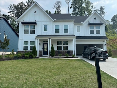 Modern farmhouse with board and batten siding, concrete driveway, a front yard, a garage, and stone siding