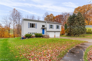 Raised ranch featuring driveway, a front lawn, and an attached garage